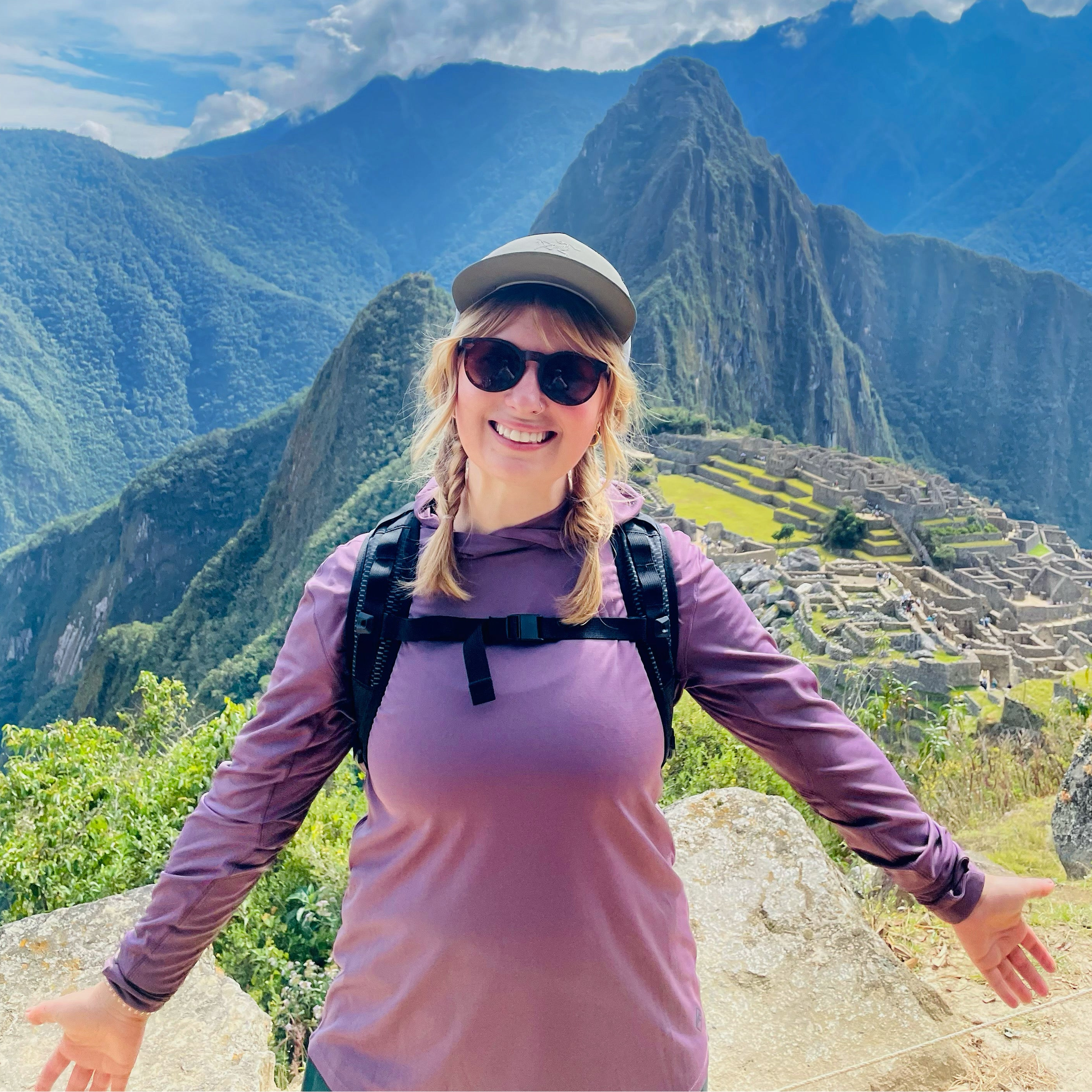 Kacie wearing a purple shirt with a backpack standing in front of Machu Picchu
